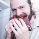 Man with ponytail biting into raw meat